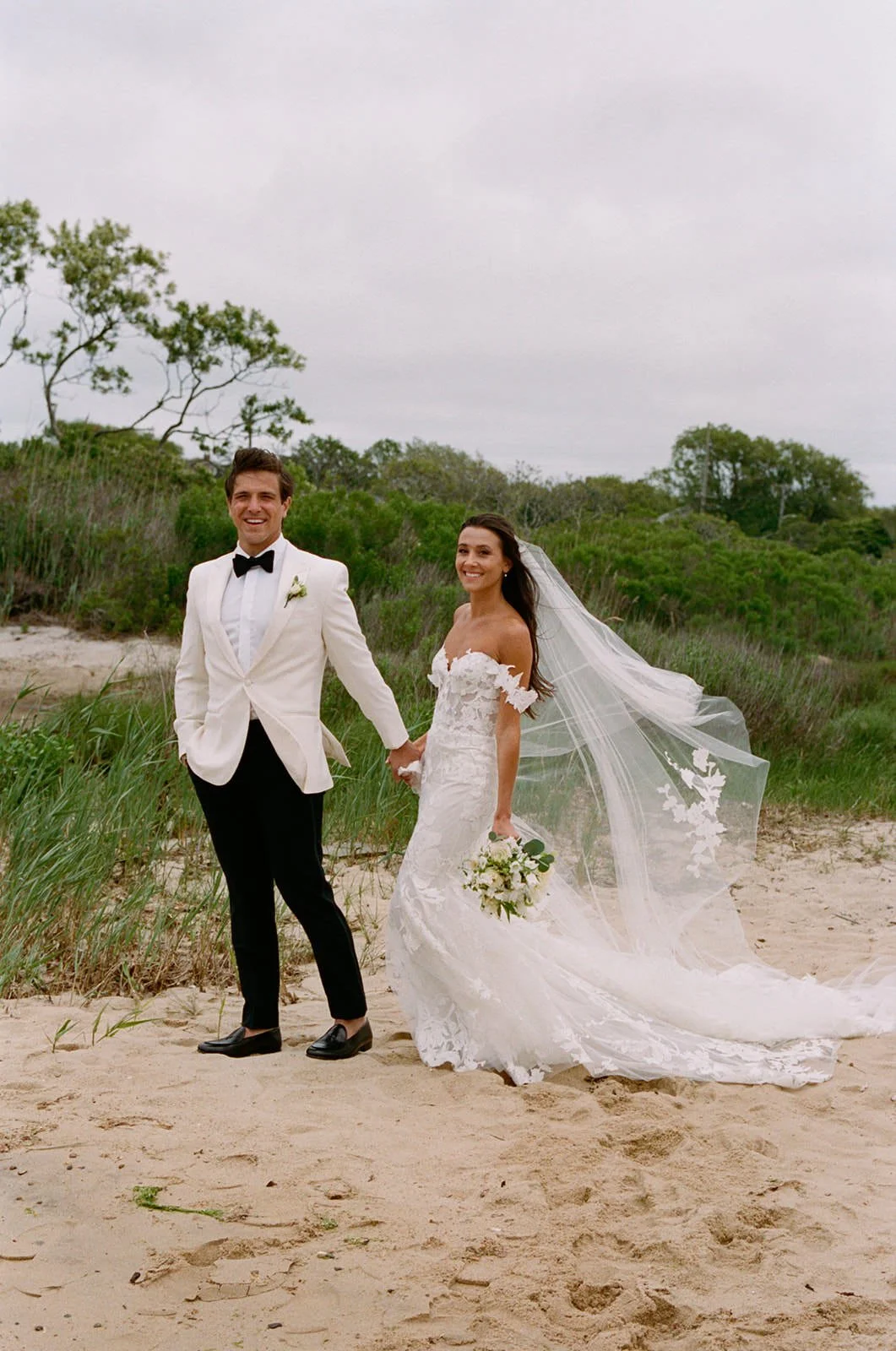 Bride and groom with her veil blowing in the wind at their Crow's Nest wedding in Montauk