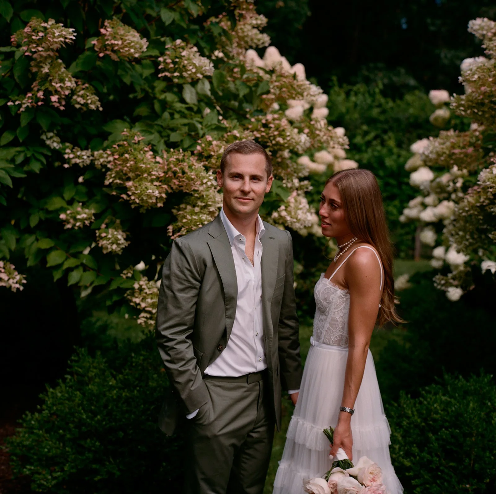 Bride and groom standing among tall white hydrangeas at Southwood Estate in Germantown, NY