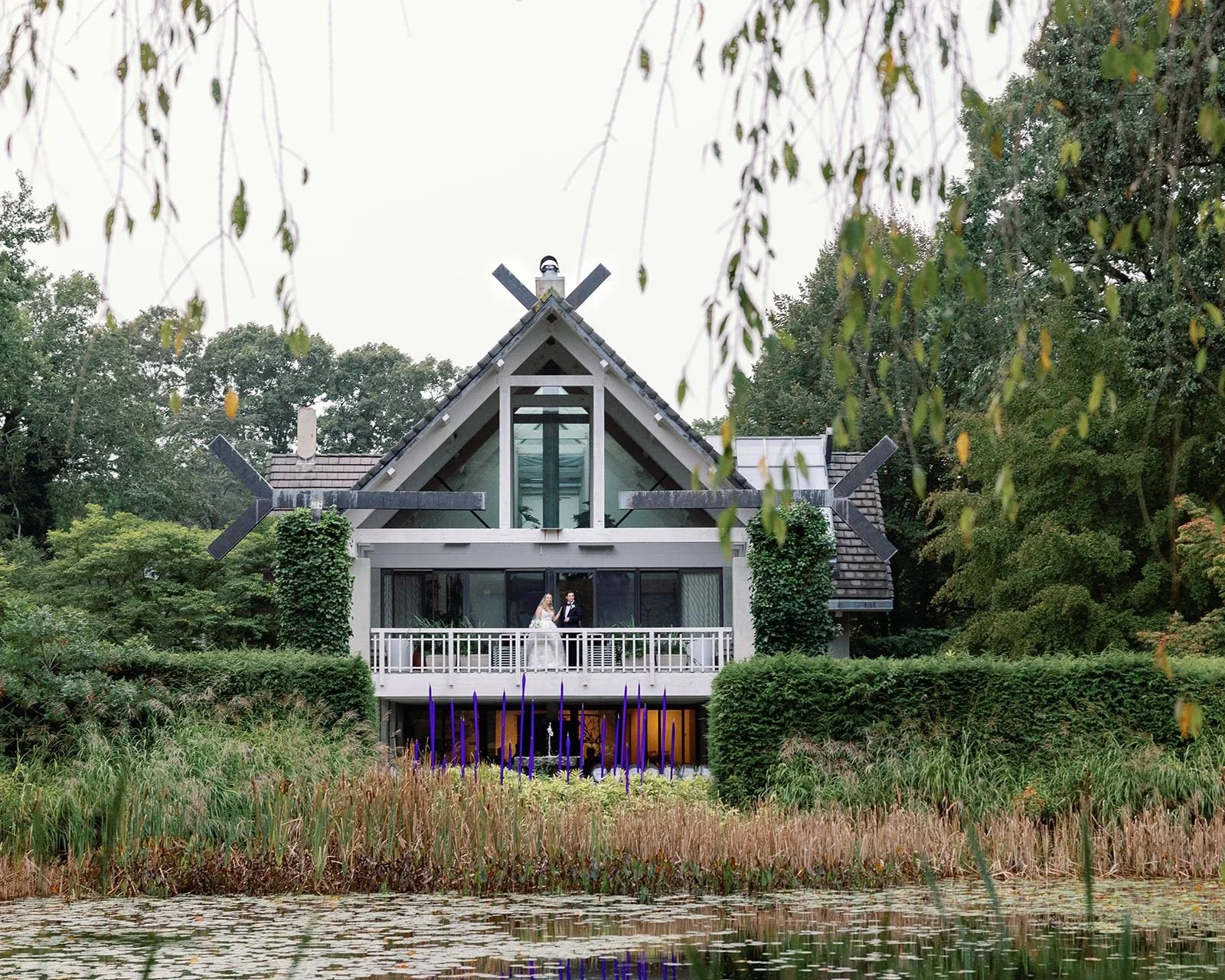 Couple on the balcony of the main house above the lily pond at LongHouse Reserve