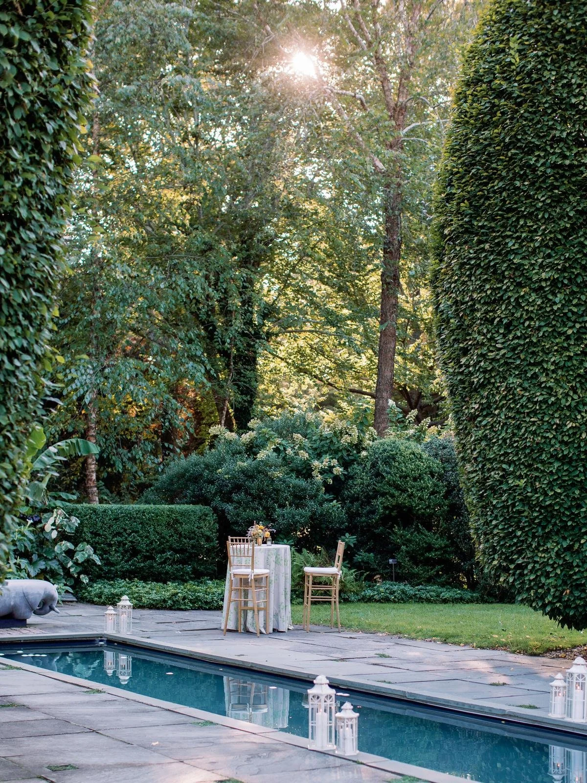 Garden pool lined with lanterns and a clipped hedge in East Hampton
