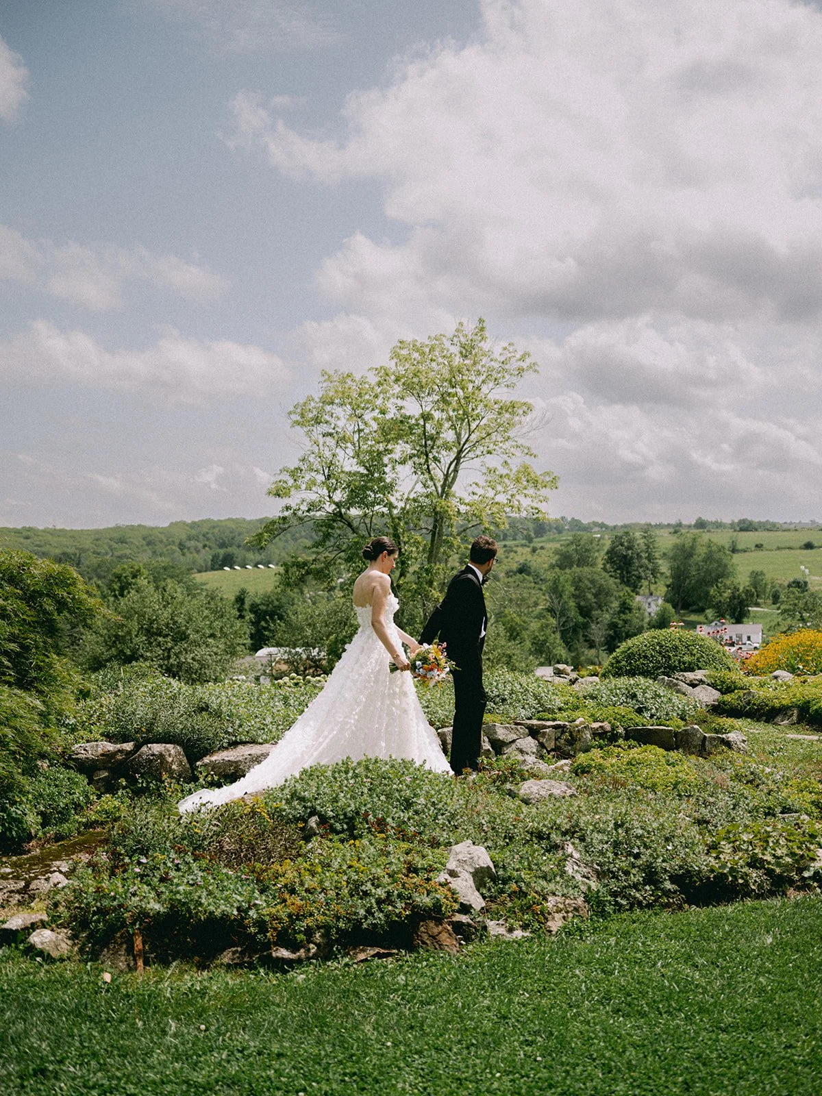Bride and groom in the gardens with rolling hills behind them at Glynwood Farm in Cold Spring, NY