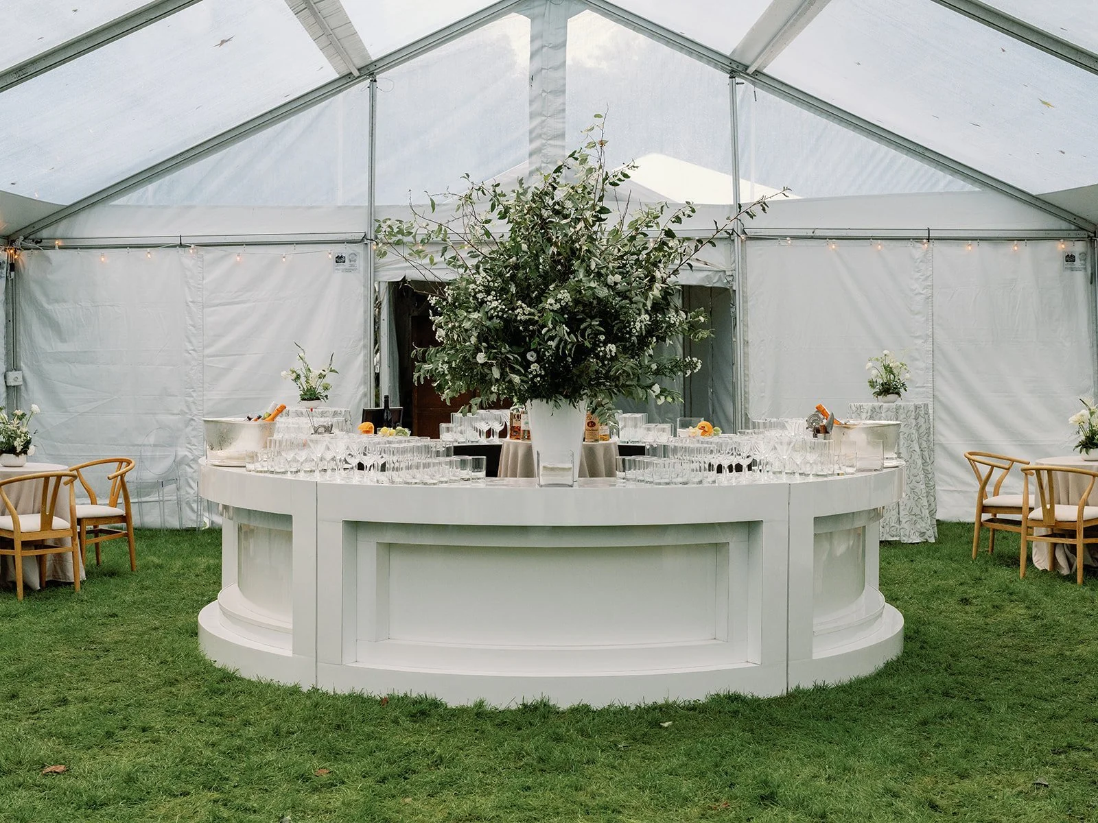 Round white bar under a clear tent on the lawn at LongHouse Reserve