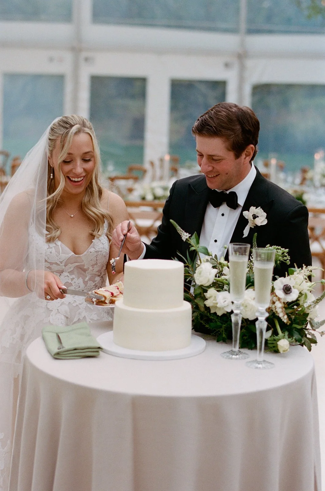 Bride and groom cutting a two-tier cake in the empty tent during cocktail hour
