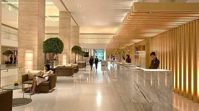 Hotel lobby with seating area, reception desk, and people walking and sitting.