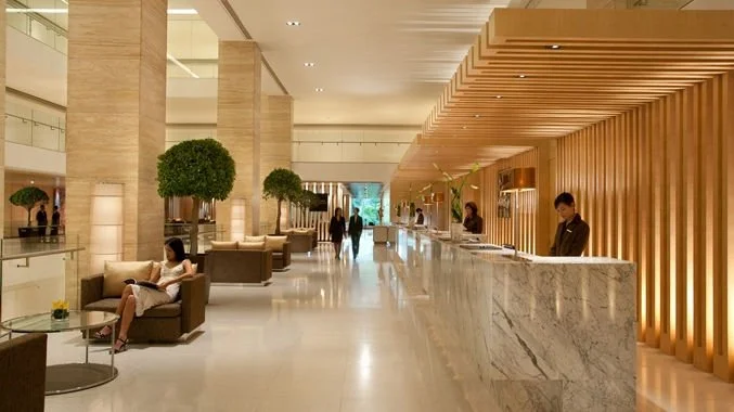 Hotel lobby with seating area, reception desk, and people walking and sitting.