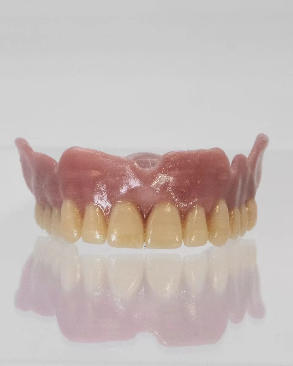 A set of dentures, with pink gum-colored base and teeth. Both materials are from Novus life sciences medical grade PETG.