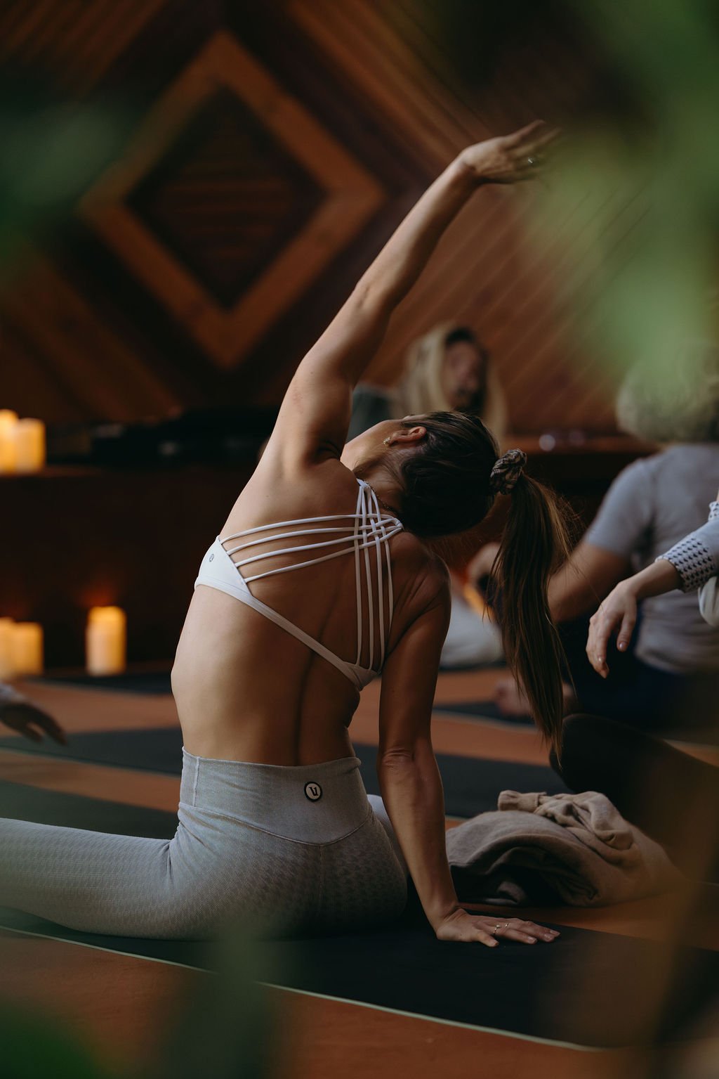 Group of people participating in a yoga class inside a wooden studio.