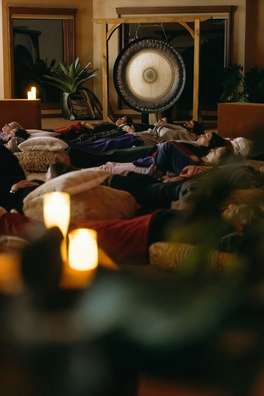 A woman singing into a microphone during a performance or open mic event in a room with wooden paneled walls and acoustic panels.