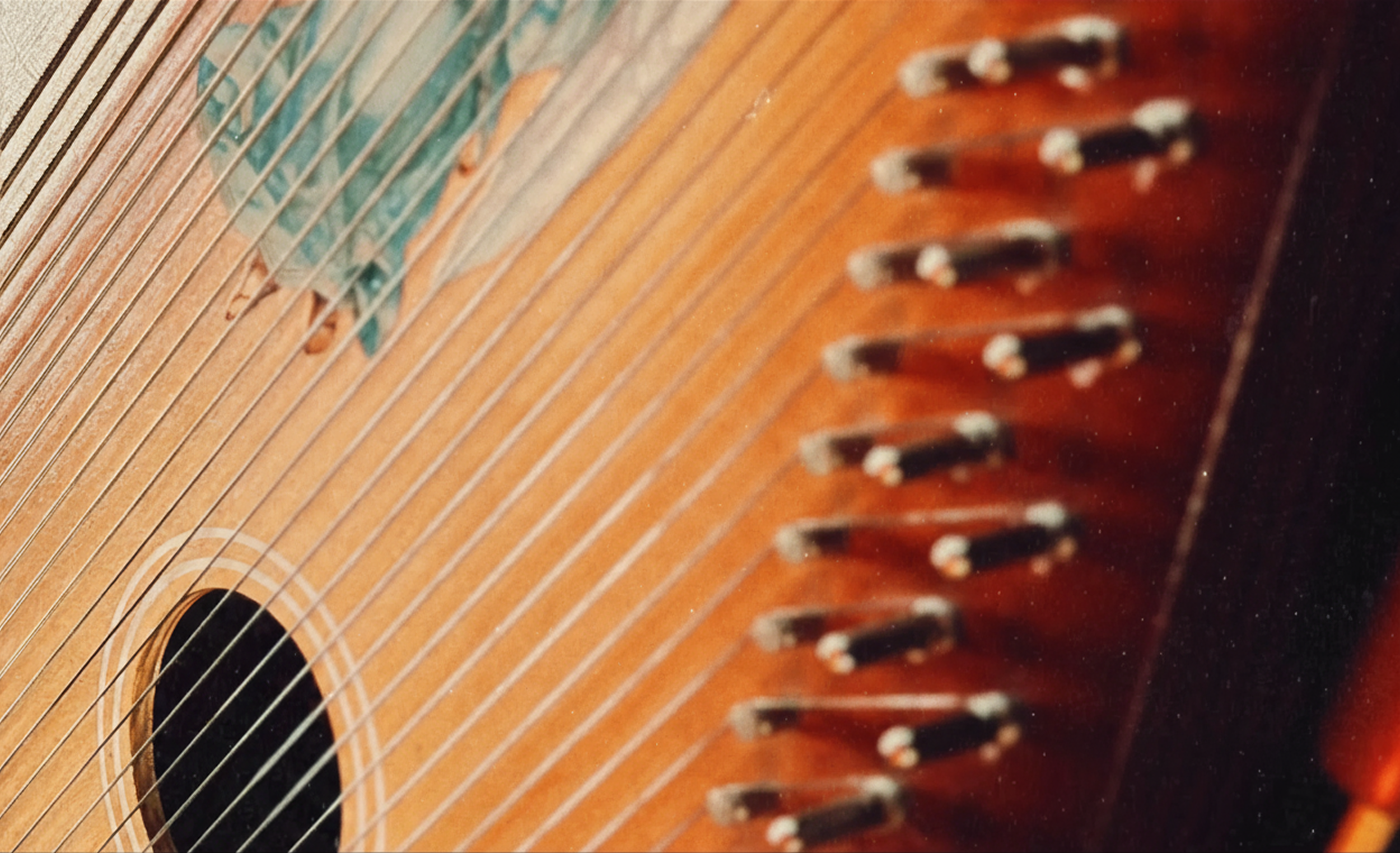Close-up of an acoustic guitar's soundboard, strings, and tuning pegs.