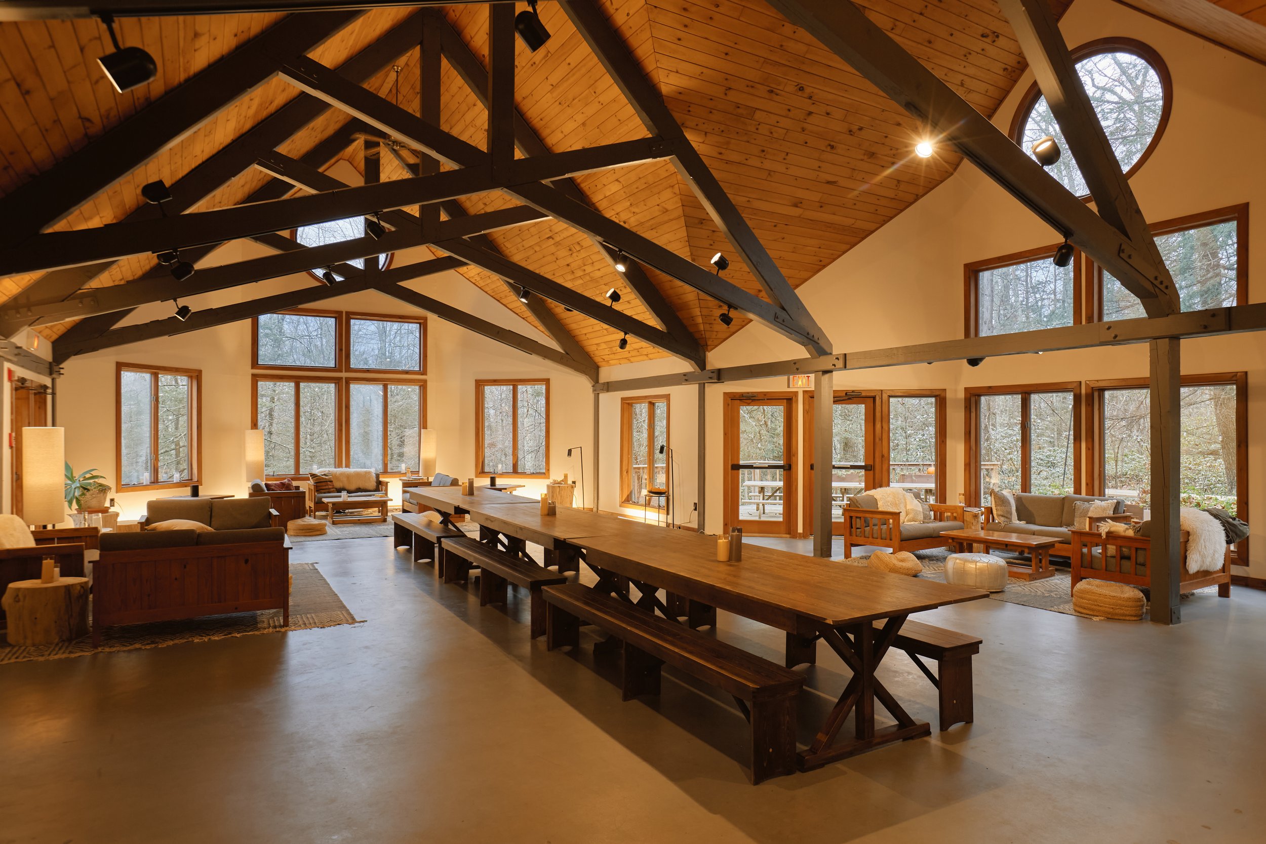 A long dining table set for a meal with candles, floral centerpieces, plates with food, and glasses in a dimly lit room.