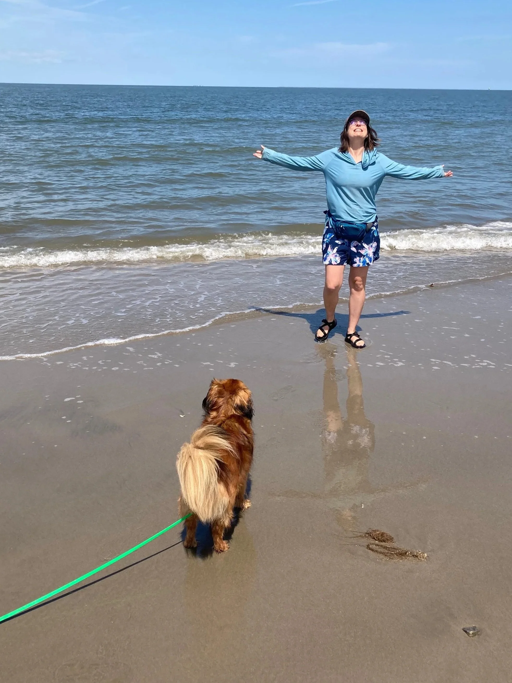 a woman at the beach with her dog.