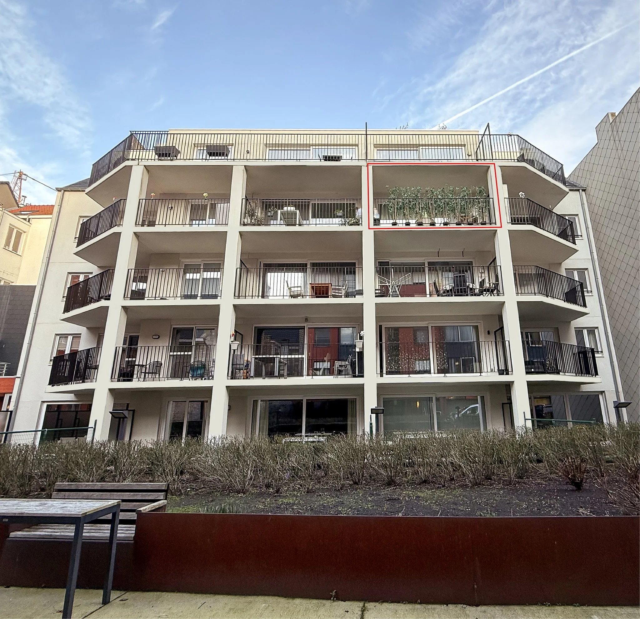 Foto van een vier verdiepingen tellend appartementencomplex met balkons, waarbij een balkon op de bovenste verdieping is gemarkeerd met een rode rechthoek, vertigo oostende, vertigo, appartement oostende, appartement te koop