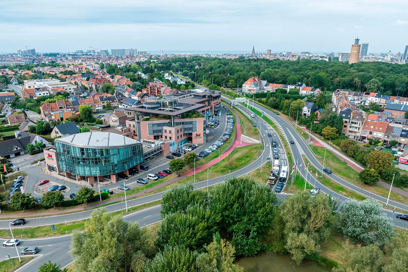 Een wit vier verdiepingen tellend appartementencomplex met balkons en een tuin op de begane grond, onder een blauwe hemel, appartement vertigo te koop, appartement oostende te koop