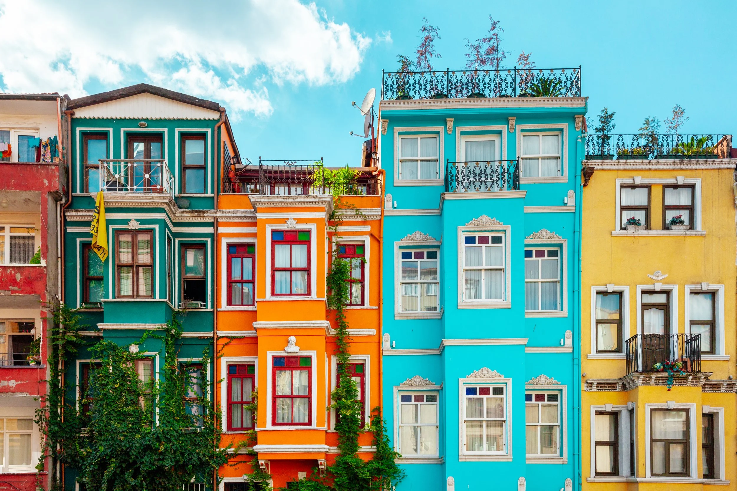 Bunte Mehrfamilienhäuser mit bunten Fassaden und Balkonen unter blauem Himmel.