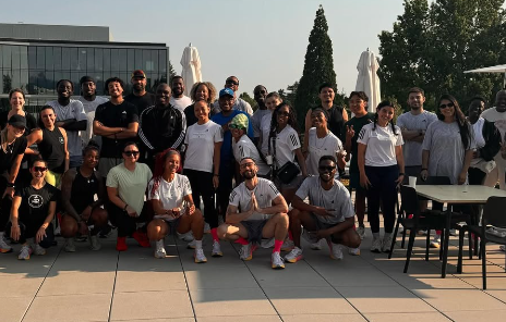 RC Members at addidas promotional 2k run. Group of people posing outdoors, some wearing sports attire, others in casual clothing, with a modern building and trees in the background.