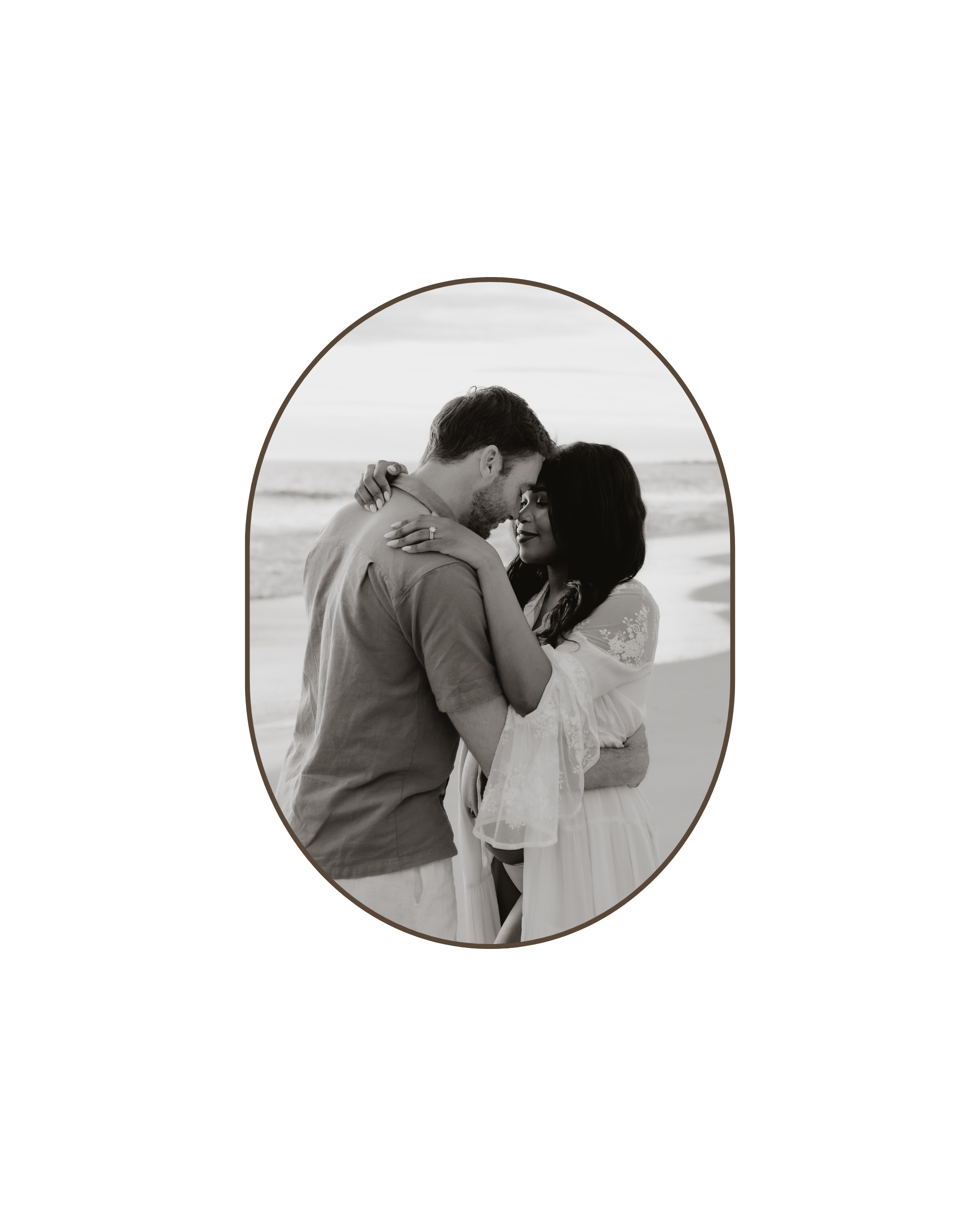 A black and white photo of a couple embracing on a beach, with their foreheads touching and eyes closed.