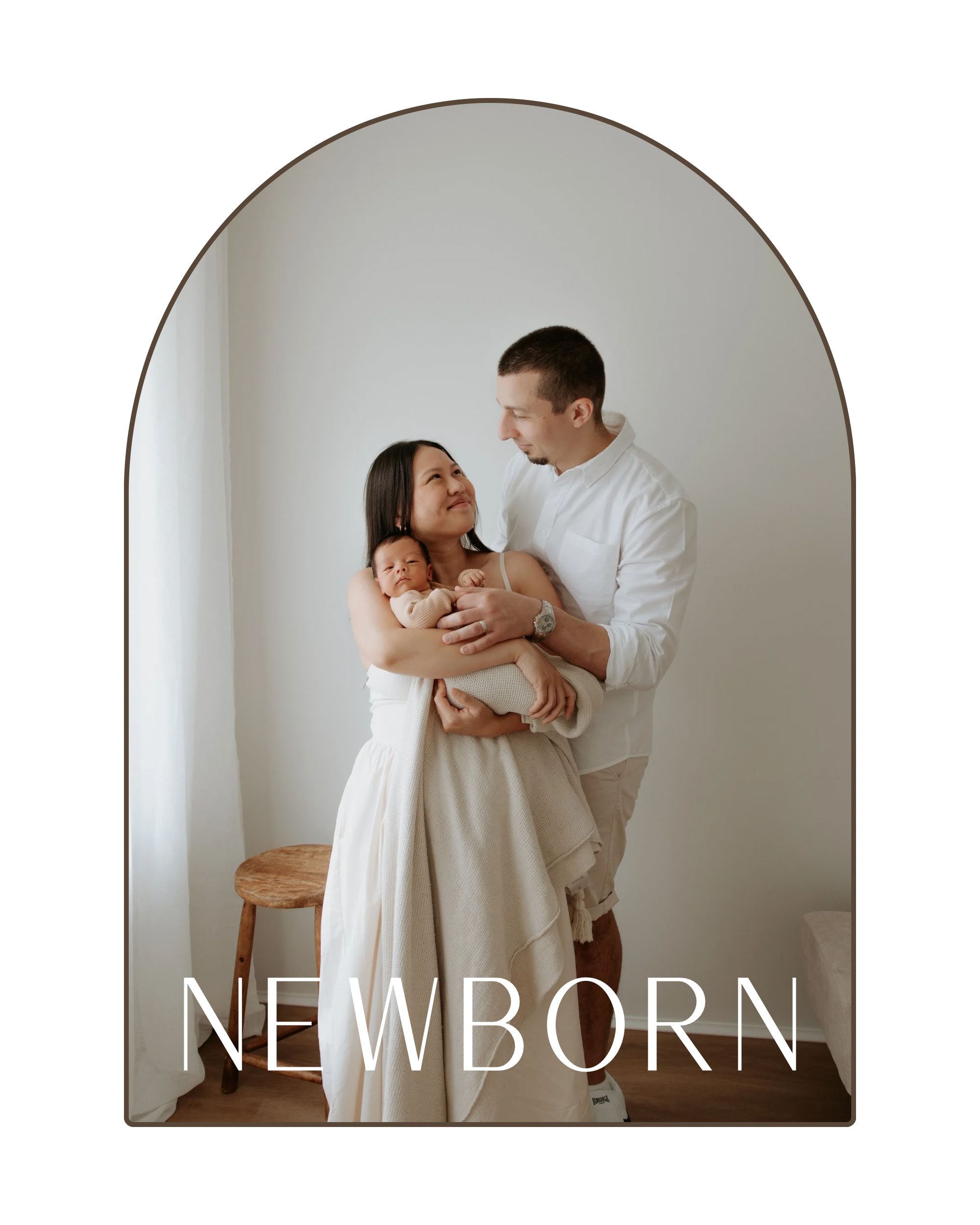 A family of three with a woman holding a newborn in her arms, standing next to a man, in a minimalistic white studio with natural light, with the word 'NEWBORN' at the bottom.