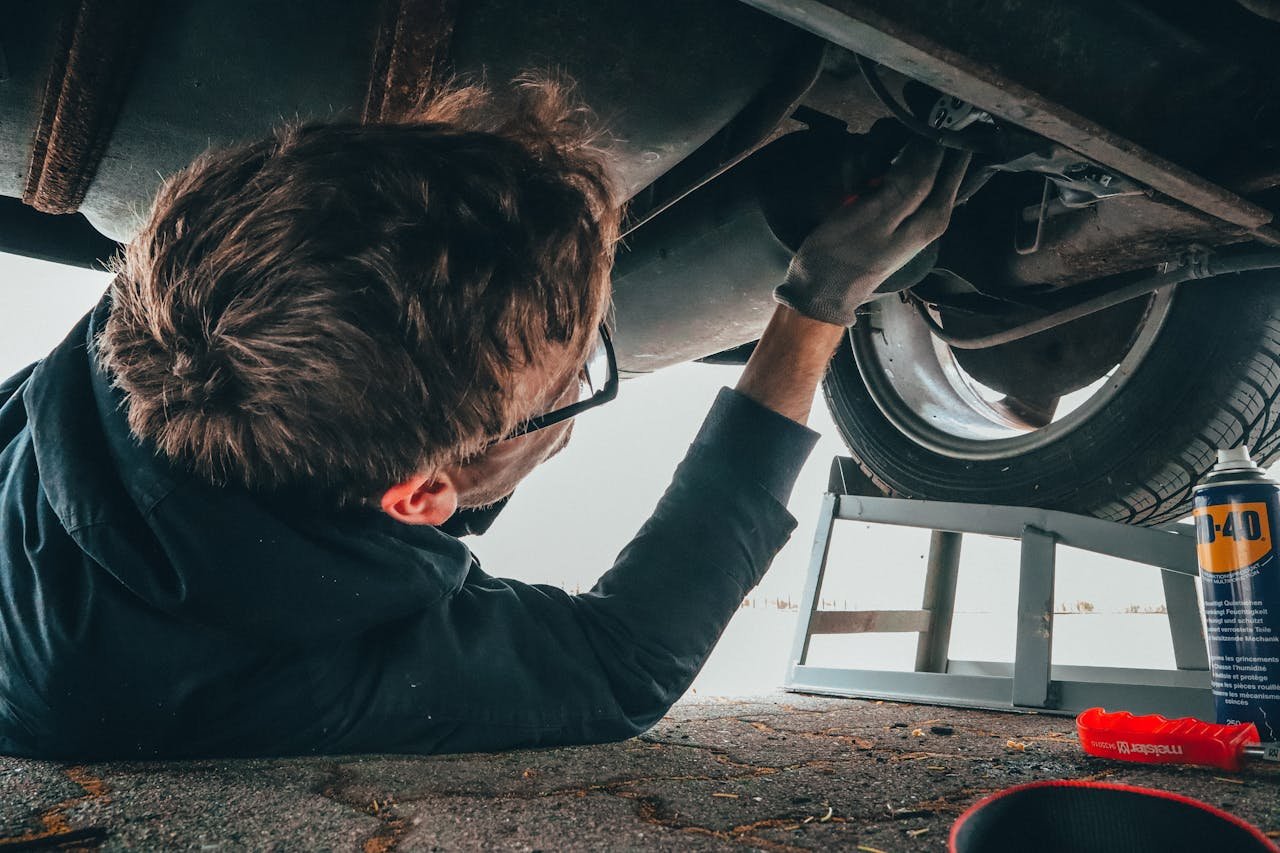 A person performing auto maintenance, working under a car.