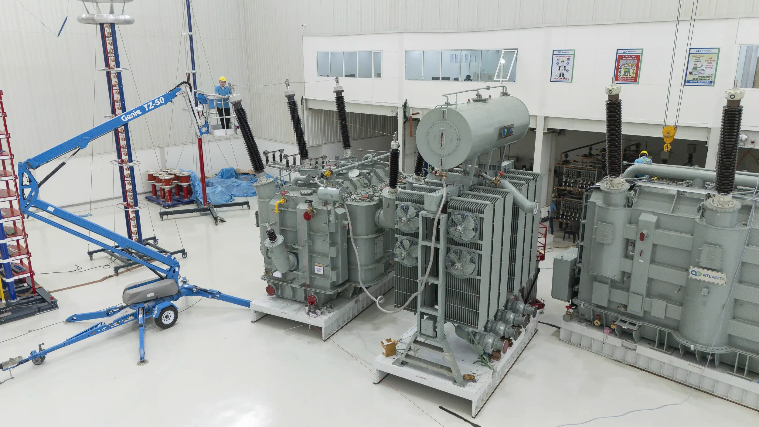 An overview of the test lab showing a technician in a lift working on a large power transformer setup.