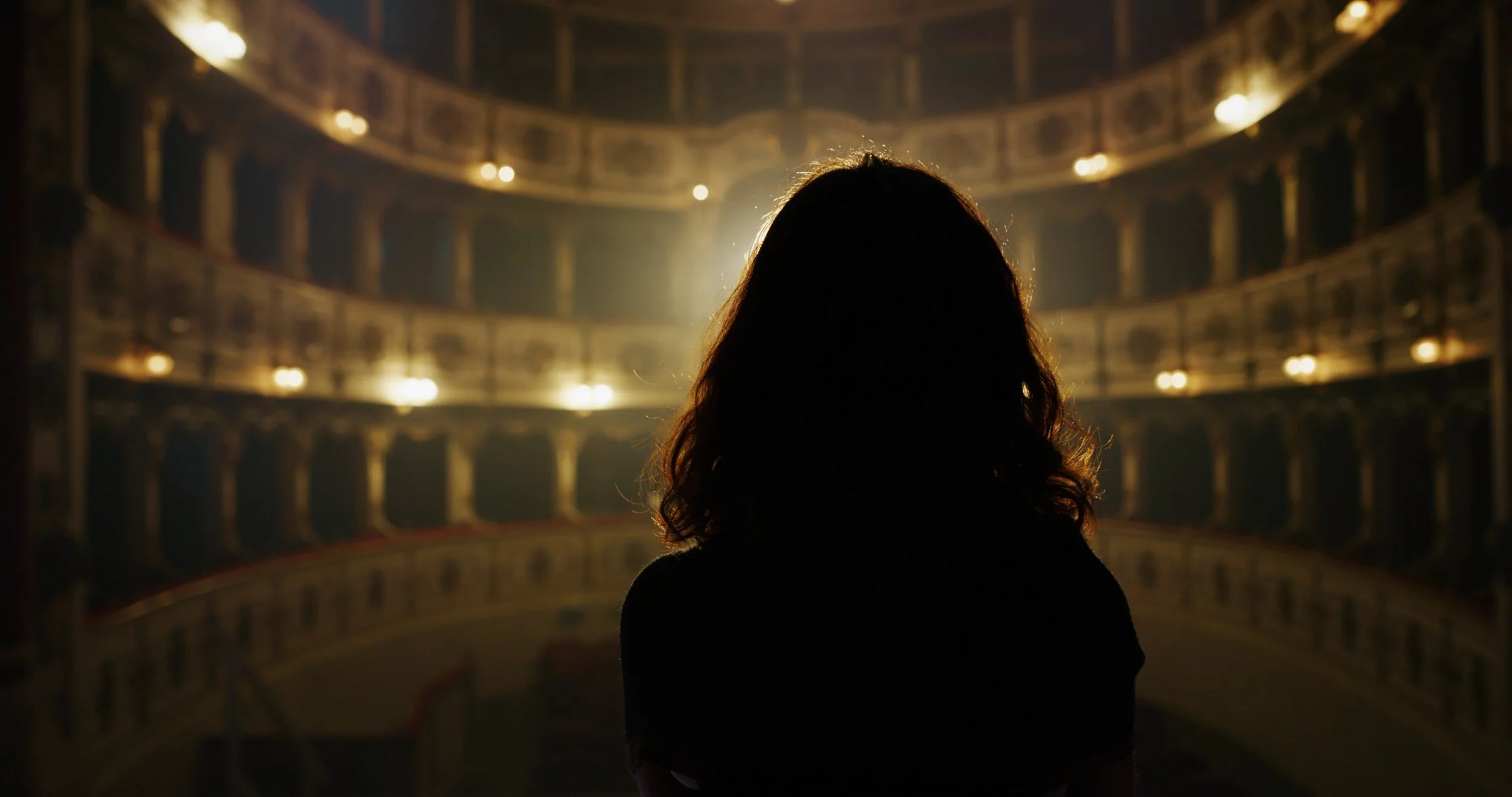 cinematic-back-view-of-female-singer-or-actress-going-on-stage-under-a-spotlight-in-an-SBI-349516074.jpg