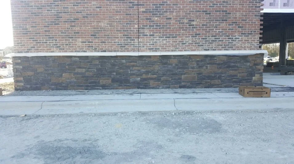 Construction site with bricks, stone wall, concrete sidewalk, and a cardboard box