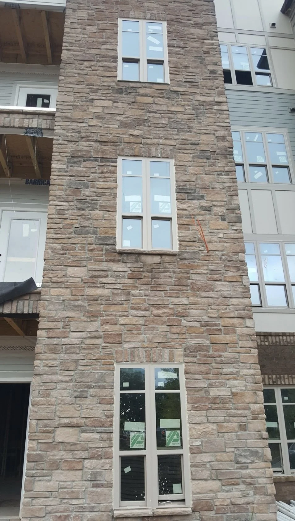A multi-story building under construction with a brick facade and multiple rectangular windows.