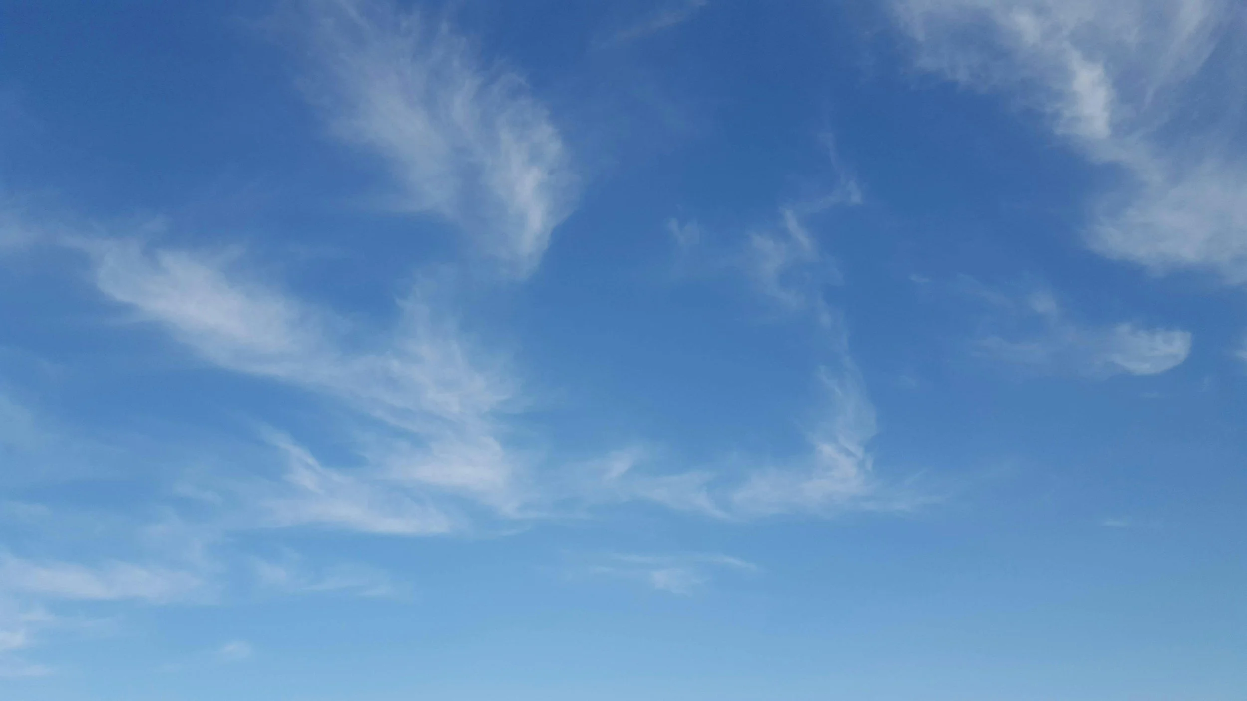 Clear blue sky with wispy white clouds.