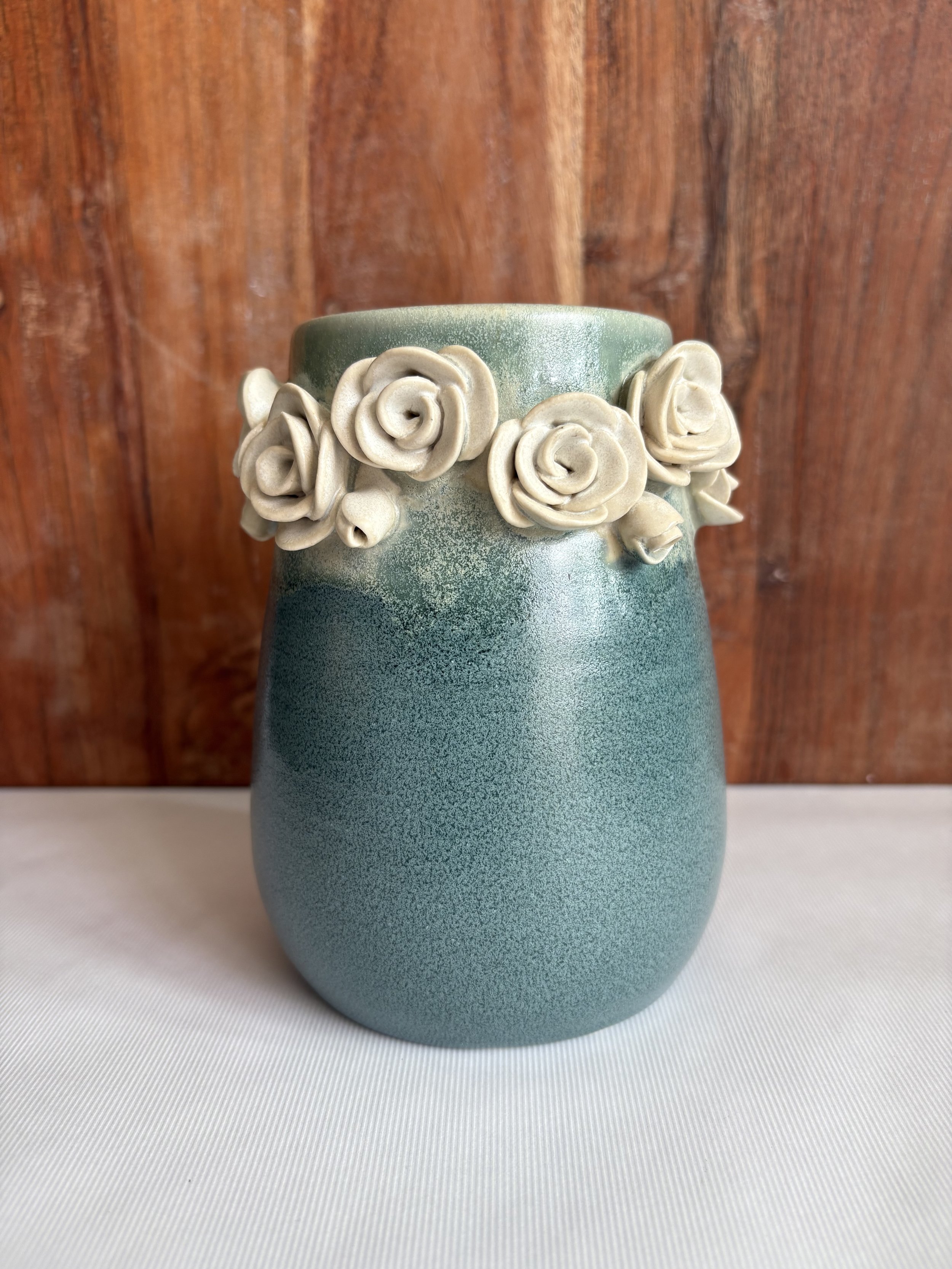 Antique blue vase with delicate white roses around the rim, adding vintage elegance.