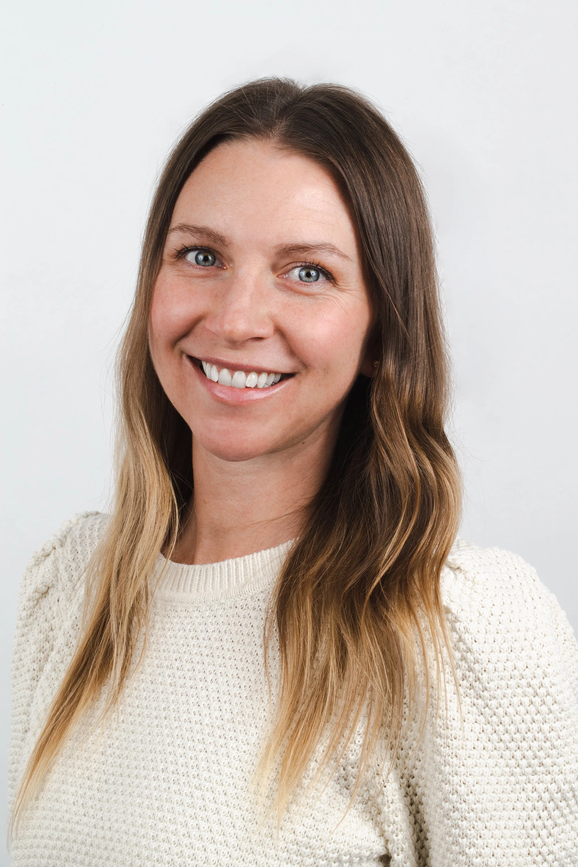 Dr Chelsey Vasquez, a woman with long wavy light brown hair and blue eyes smiling at the camera