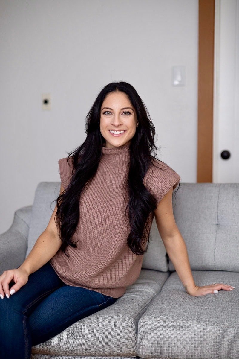 Rachel Wise, a woman with long wavy dark hair smiling and looking at the camera, wearing a pink top. 