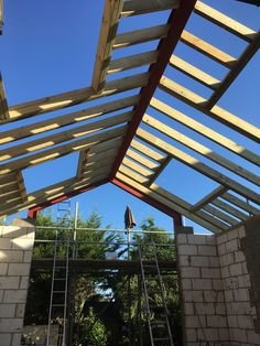 Wooden roof framework of a building under construction with ladders and clear blue sky PrimeCore builders