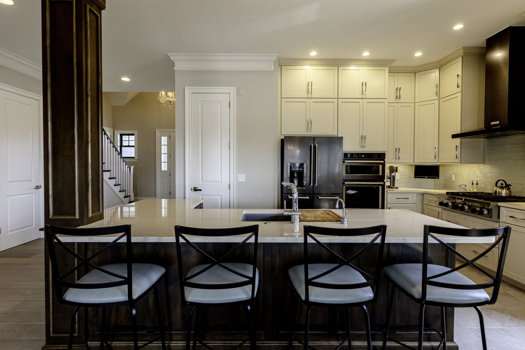 Modern kitchen with island, bar stools, stainless steel appliances, and white cabinets.