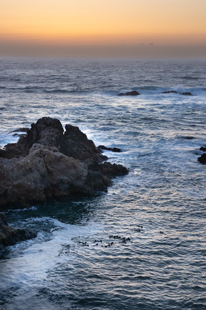 Rocky coastline with ocean waves and a sunset sky