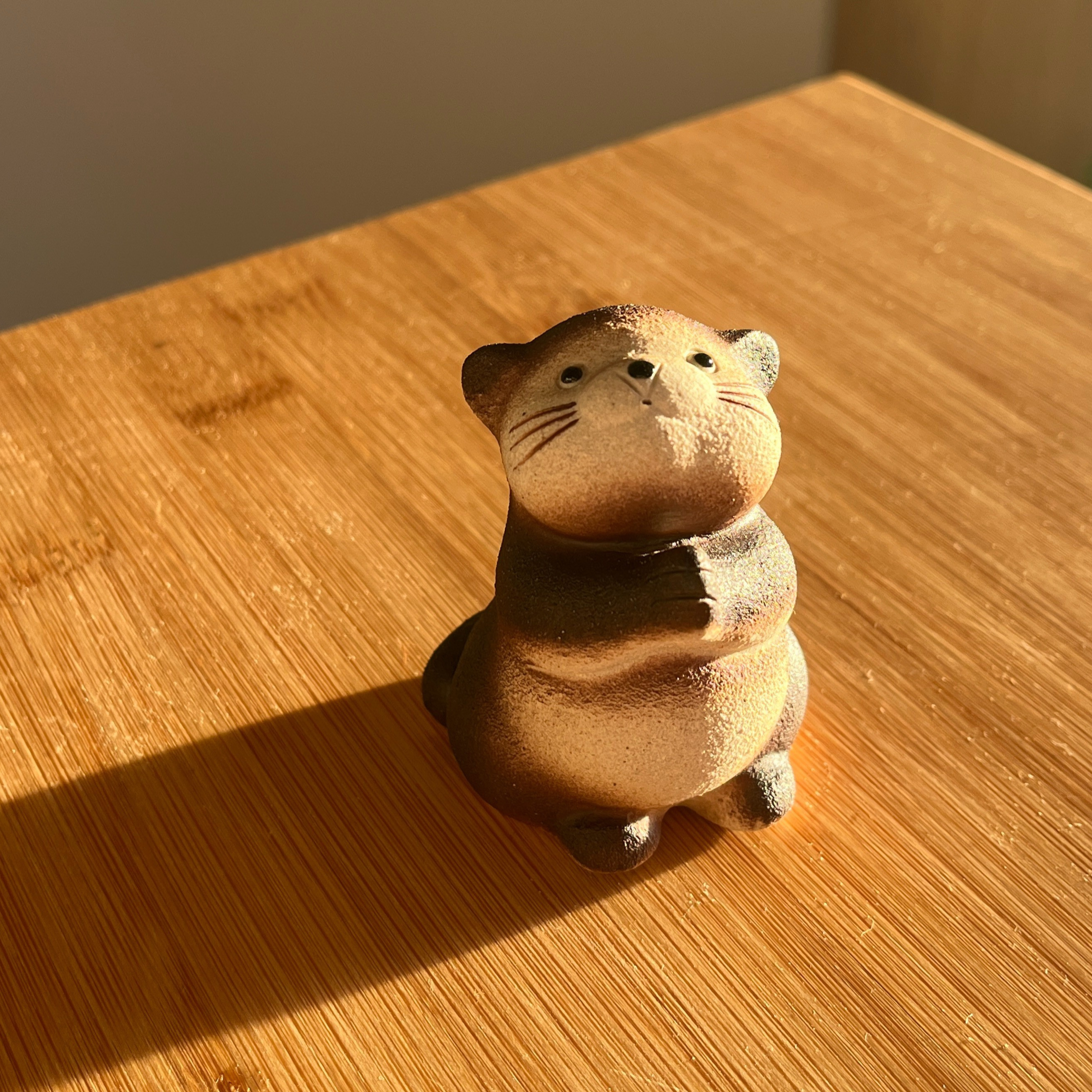 Kleine bunte Tierfigur, die an einem Holzoberfläche steht.