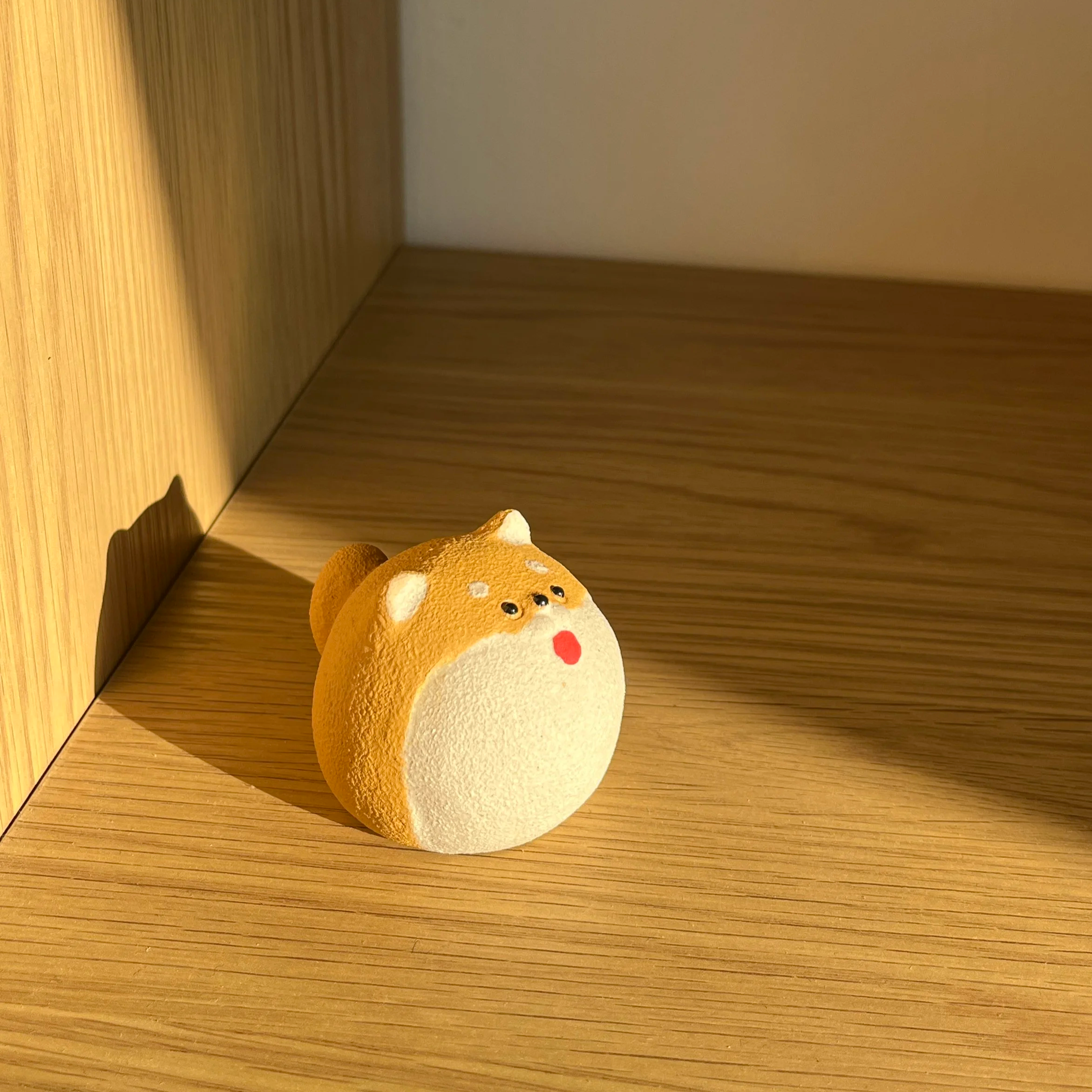 Eine süße Hundefigur auf einem Holzregal in warmen Licht.