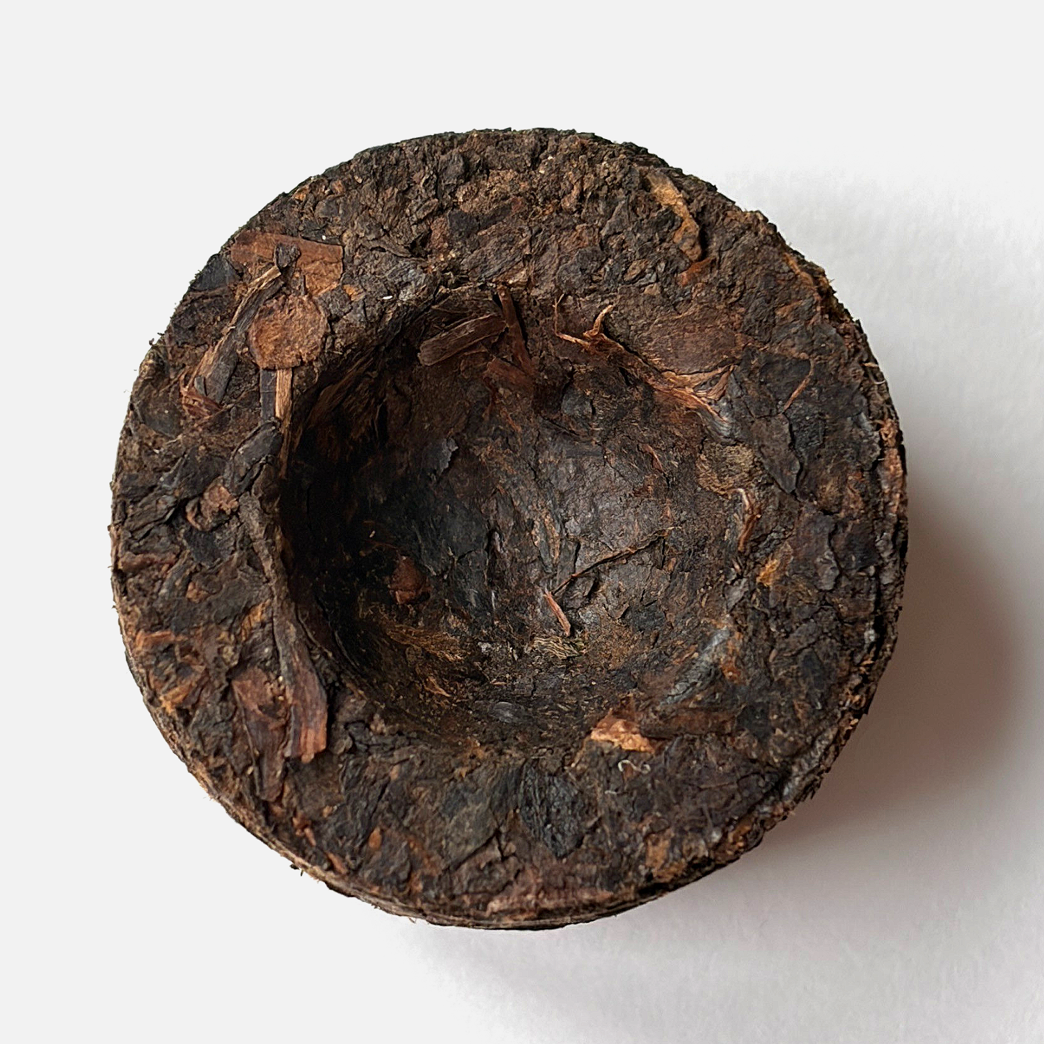 Ein runder, gepresster Puerh Tee auf weißem Hintergrund.
