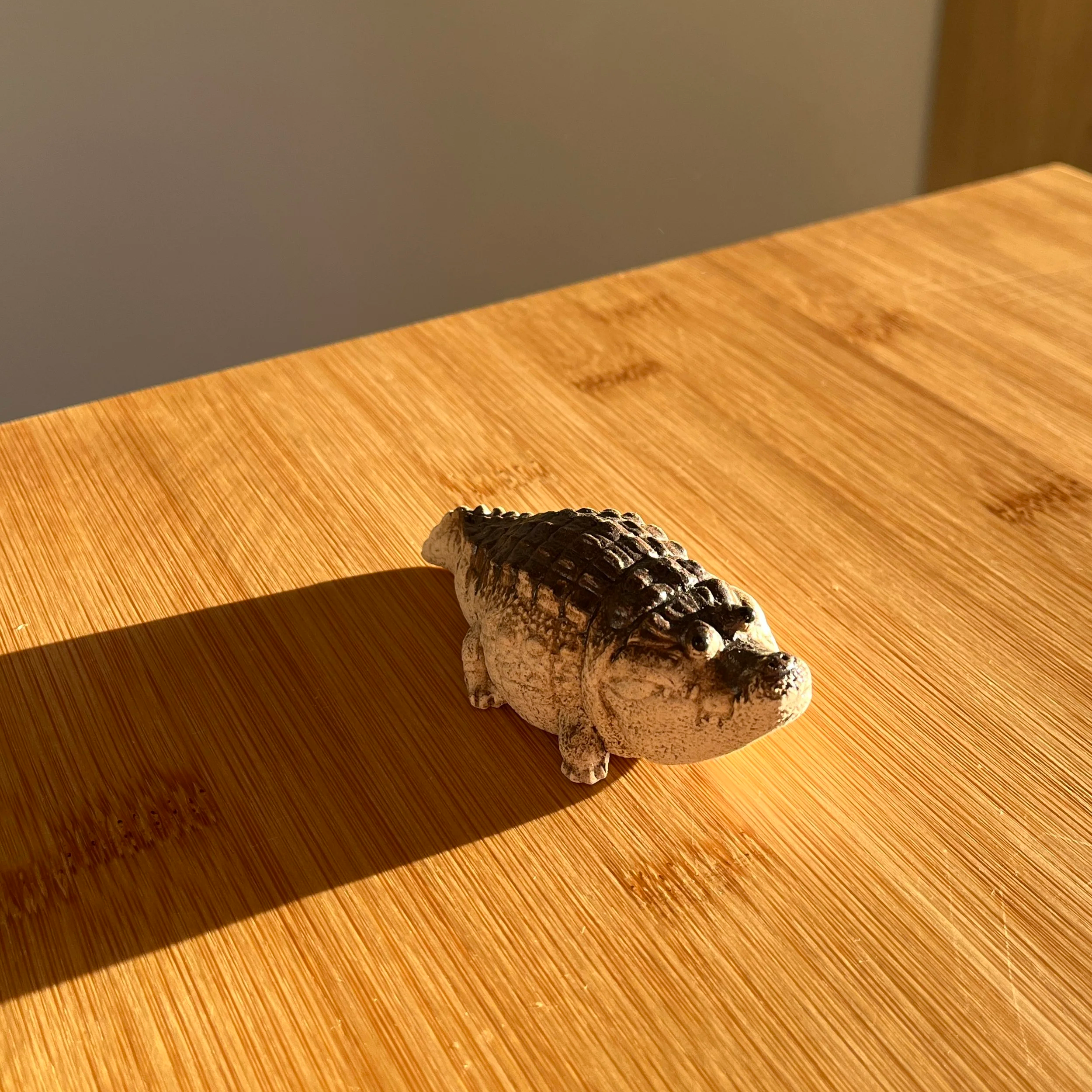 Eine Figur eines Krokodils auf Holz in warmen Licht mit Schatten.