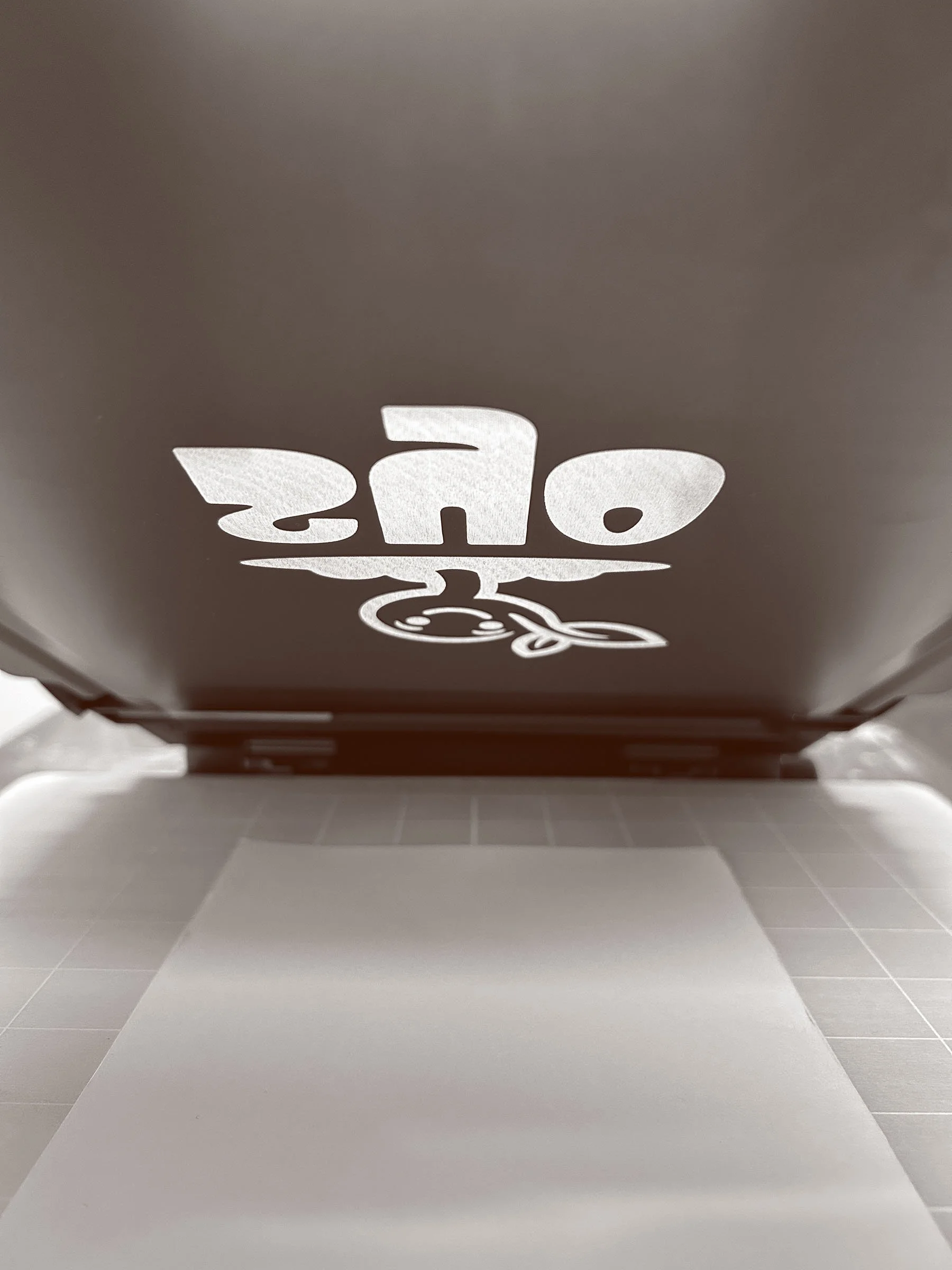 Back of a screen print showing the reversed image of the SYO logo, with a piece of paper underneith.