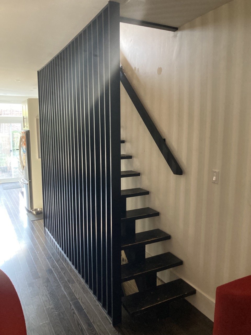Modern black stairway with slatted railing in a contemporary interior space.
