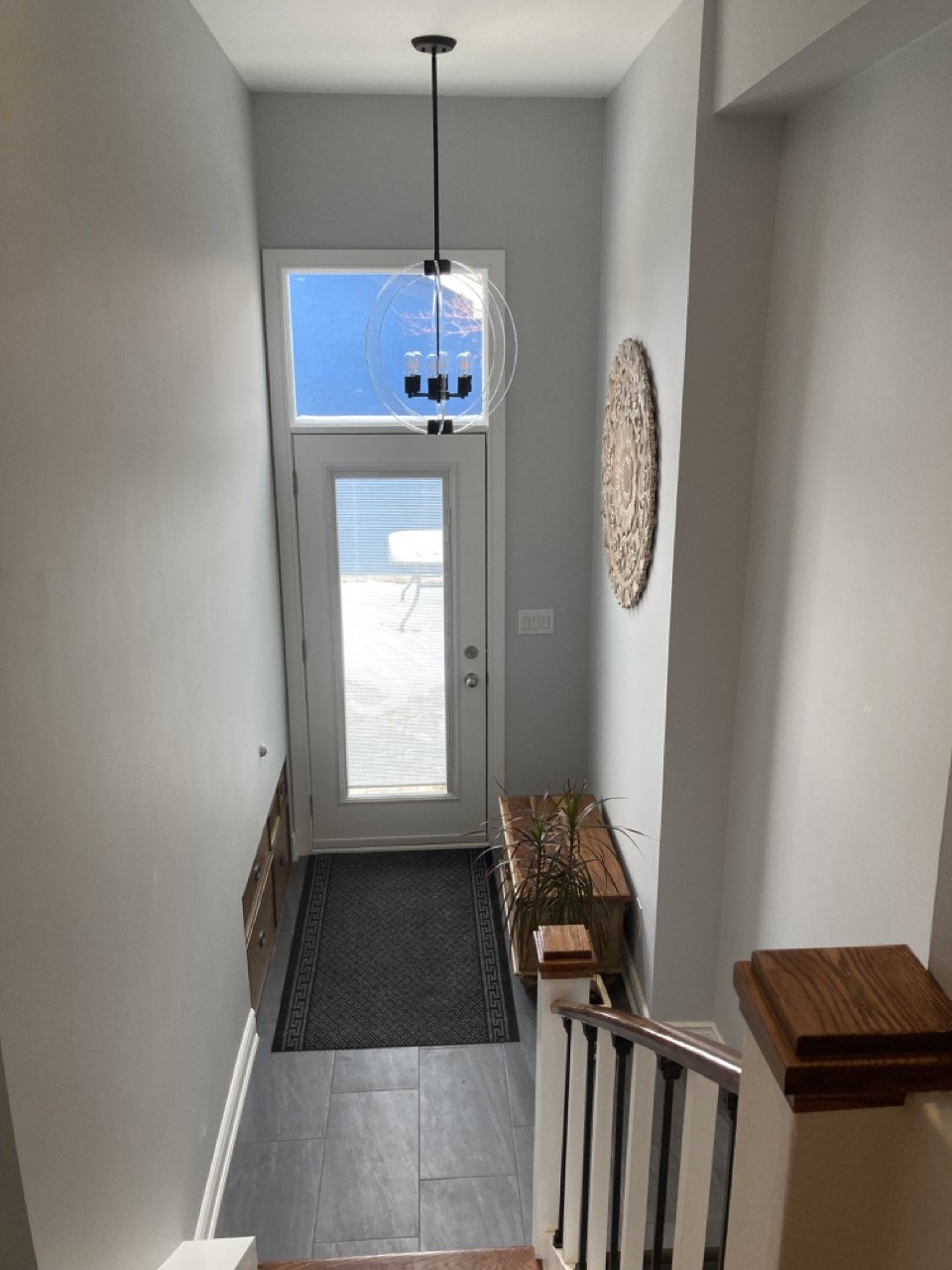 Modern entryway with staircase, wall art, bench, plant, and glass door
