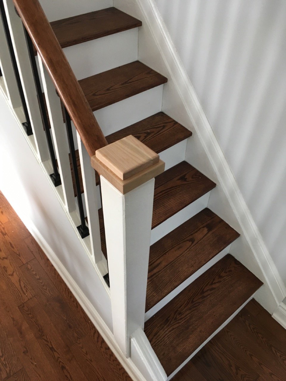 Wooden staircase with dark brown steps, white risers, and a wooden handrail.