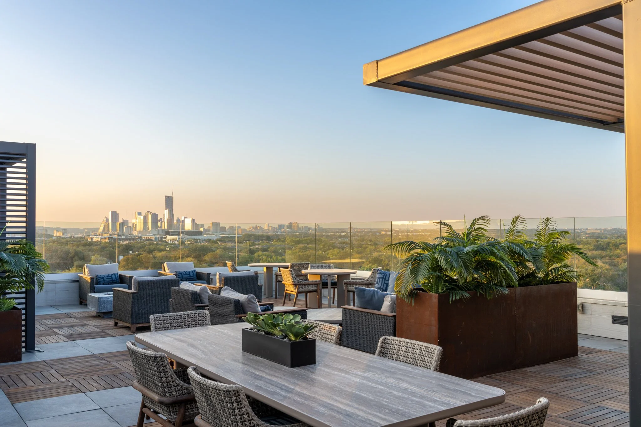 Architectural Photography featuring rooftop Patio of Zoey Apartments in Austin Texas of the terrace with outdoor seating, plants, and a view of the city skyline at sunset