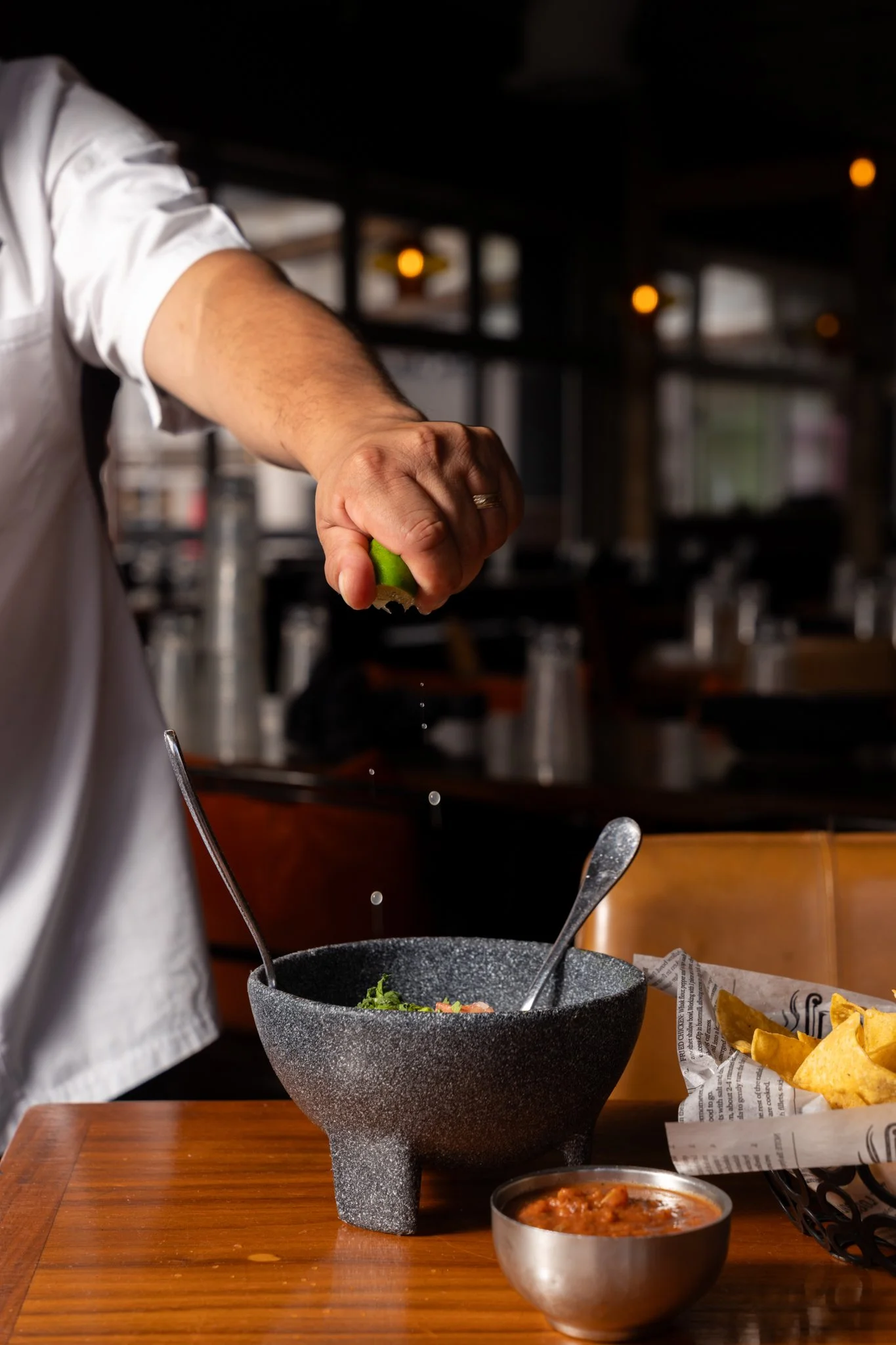 Food photography  for Richard Sandoval Hospitality restaurant Venga Venga in Aspen, CO featuring Person squeezing lime into a bowl of salad in a restaurant.