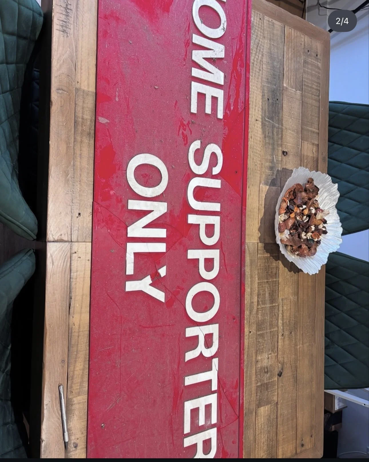 A wooden table with a red sign that reads 'ONE SUPPORTER ONLY' and a paper tray of assorted chocolates or candies.