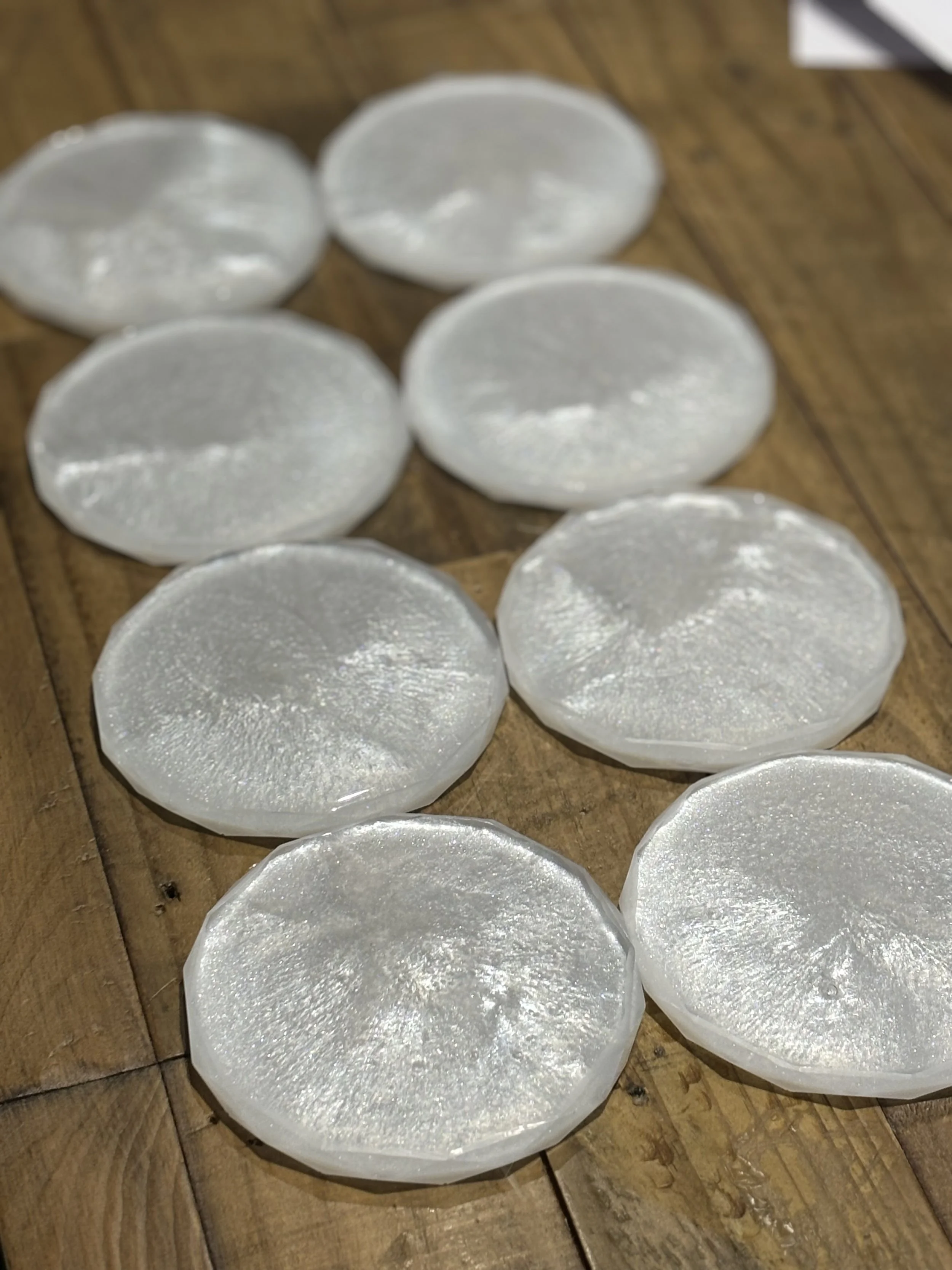 Eight translucent, round ice cubes with rough edges placed on a wooden surface.