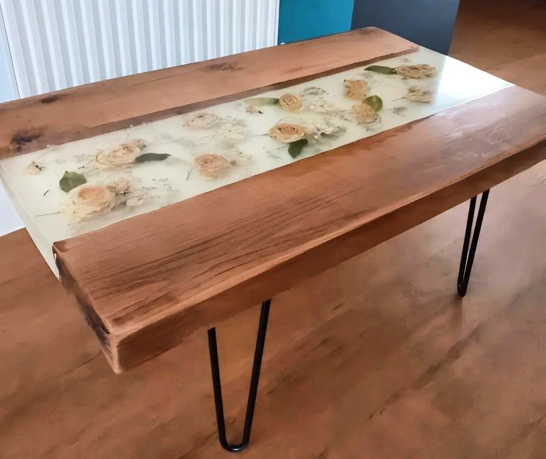 Wooden table with a resin inlay containing embedded dried flowers and leaves.