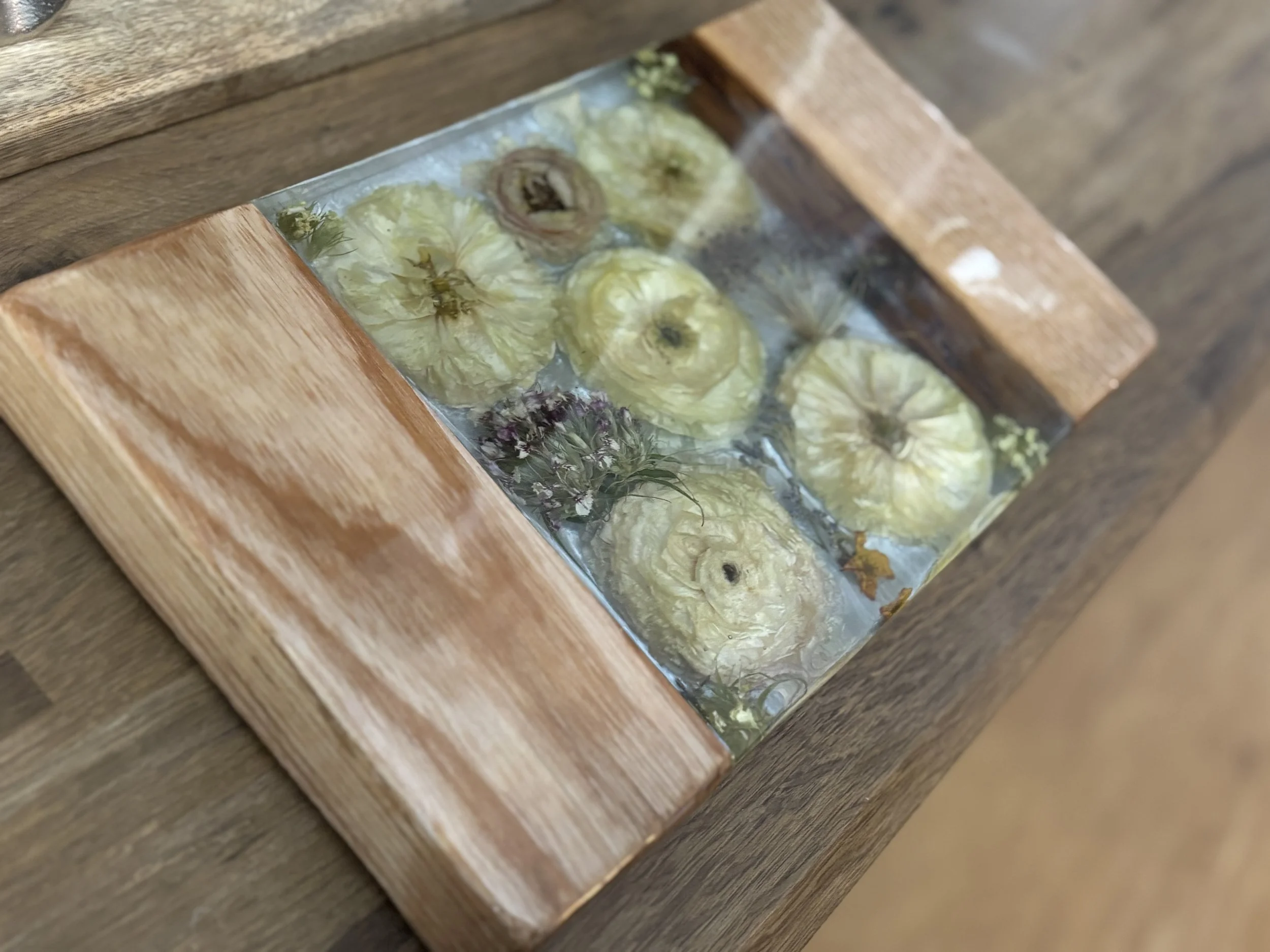 A wooden mirror with flowers inside, appearing to be water or flower preserve.