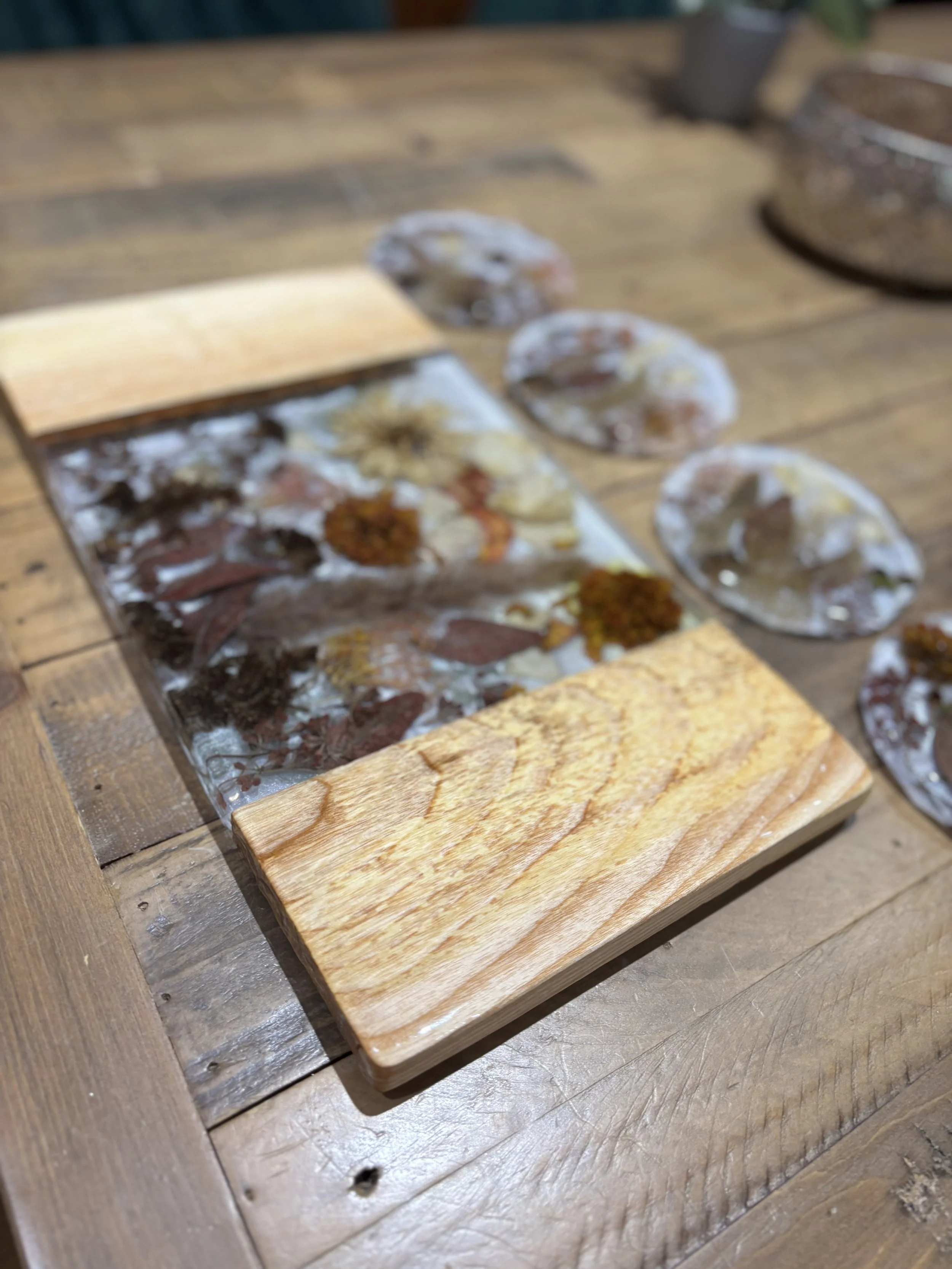 A wooden table with a small wooden cutting board in front and transparent plates with dried mushrooms and seasoning scattered around.