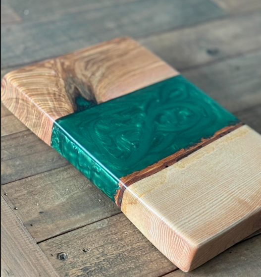 Wood and resin cutting board with green epoxy inlay on wooden table