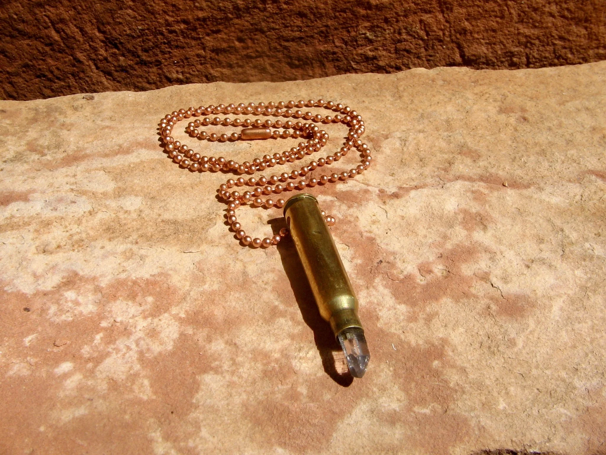 A 24" copper-chain necklace with a pendant made of a bullet casing and a small quartz crystal